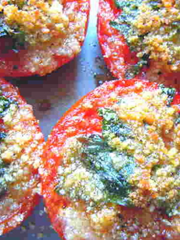 Red tomatoes cut in half, then sprinkled with herbs and breadcrumbs.