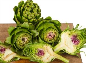 Four green and white artichokes, with one cut in half.