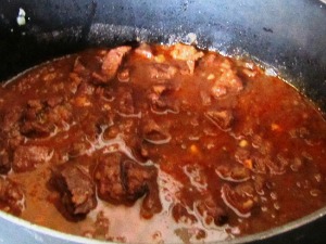 A cooking pot with red meat sauce.