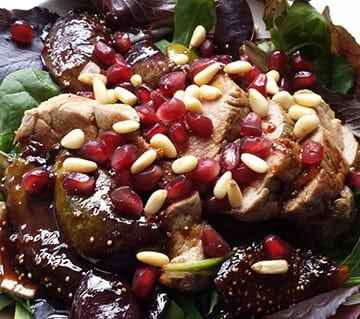 Pork loin with figs covered in a dark balsamic sauce sprinkled with pine nuts.
