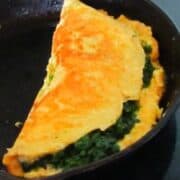 A golden yellow omelette with green spinache filling.