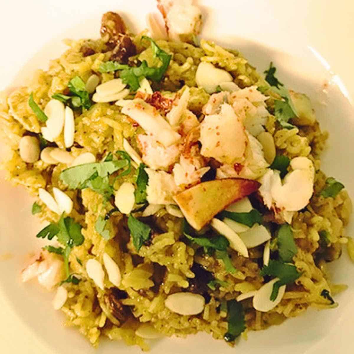 White bowl filled with a mix of green herbs, spices, chicken pieces and yellow rice.