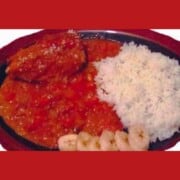 Red plate full of white rice, chicken breast covered in red sauce with slices of bannana along the side of the plate.