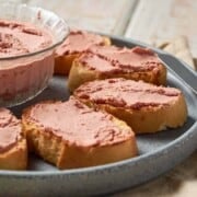 Grey stone plate with slices of oval toast, buttered with smooth brown pate.