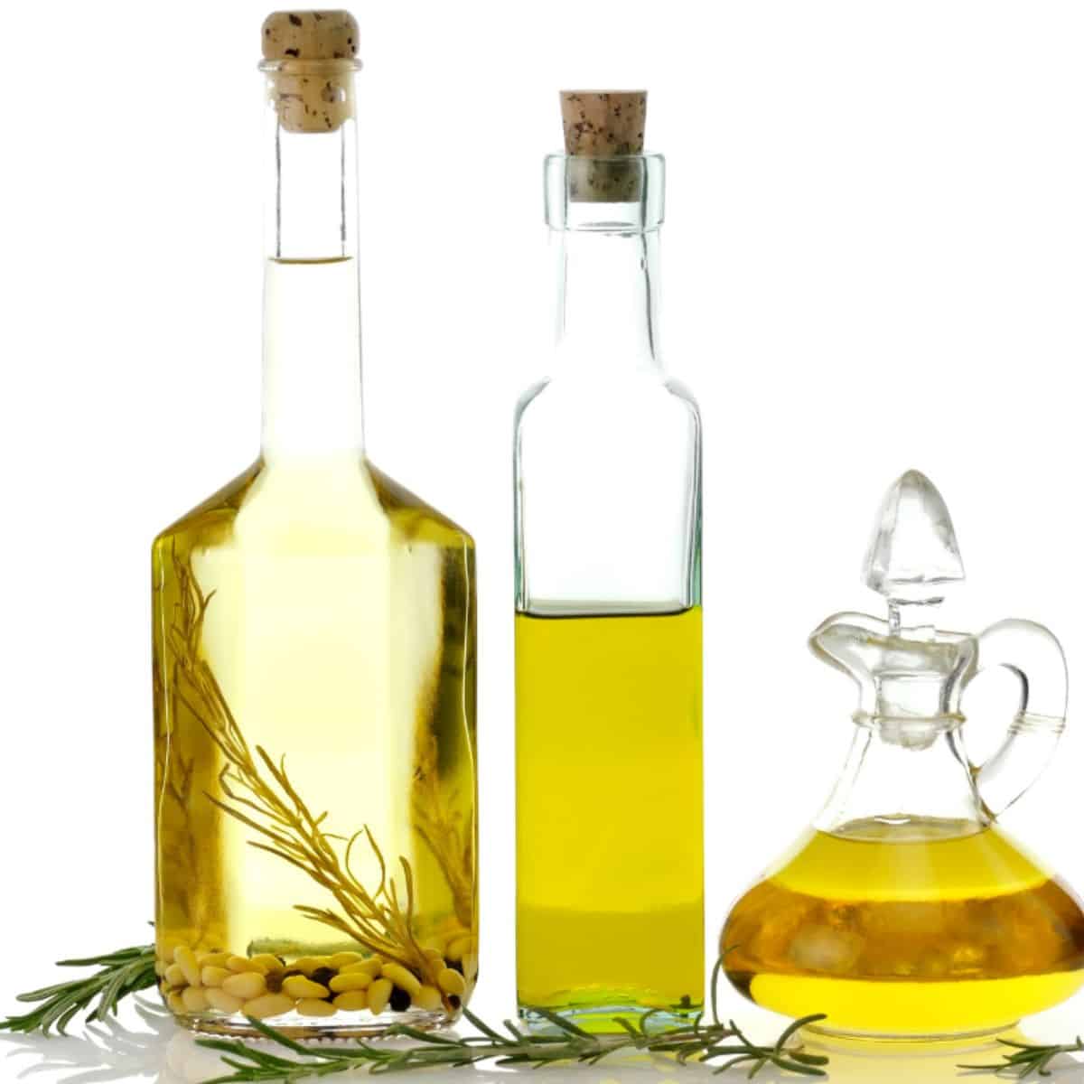 Three bottles with yellowish oils for cooking.