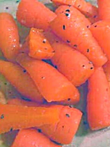 A serving of small, orange, rectangular shaped carrots with specks of parsley.