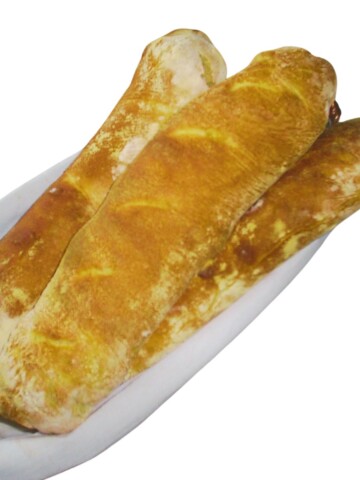Three long narrow loaves of bread on a long white platter.