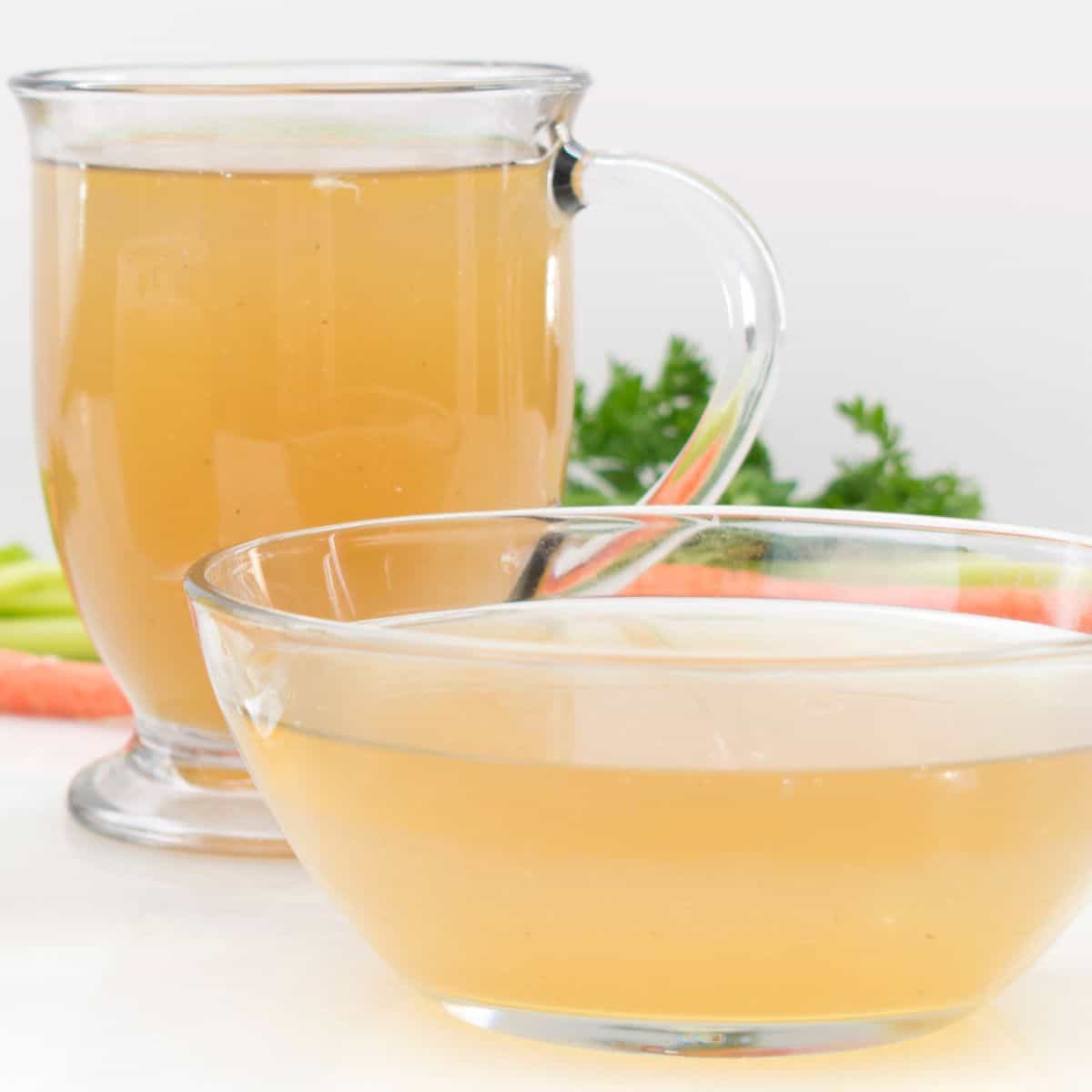 A cup and bowl of clear light brown chicken broth.