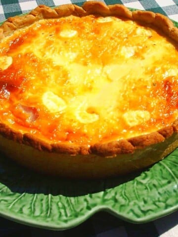 A large green platter holding a quiche with brown crust and golden yellow filling