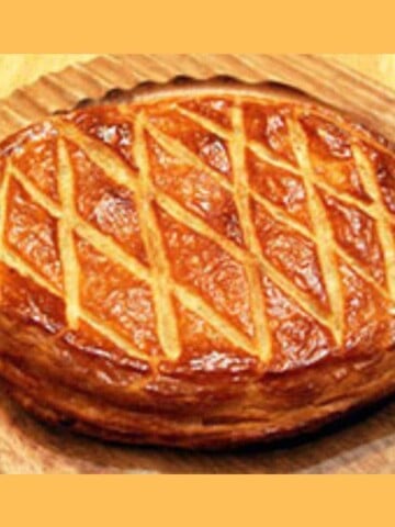 A flat pastry cake with a shiny top on a wooden platter.