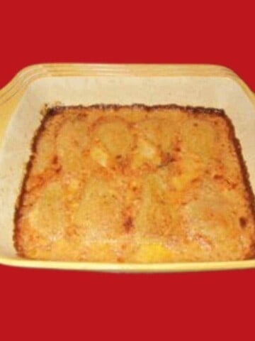 Yellow and white baking dish with baked fruit on a red background.