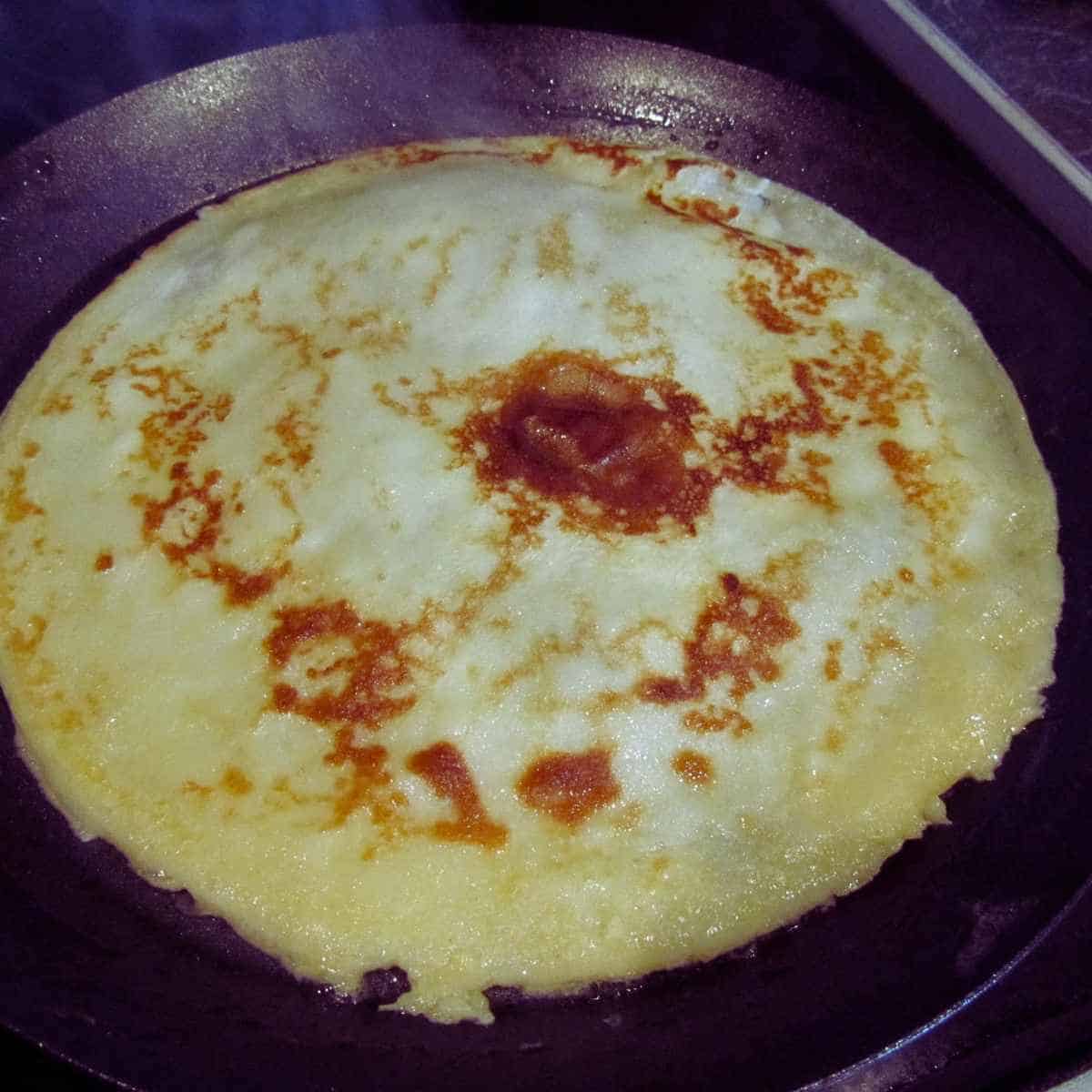 Browned crepe in a frying pan.