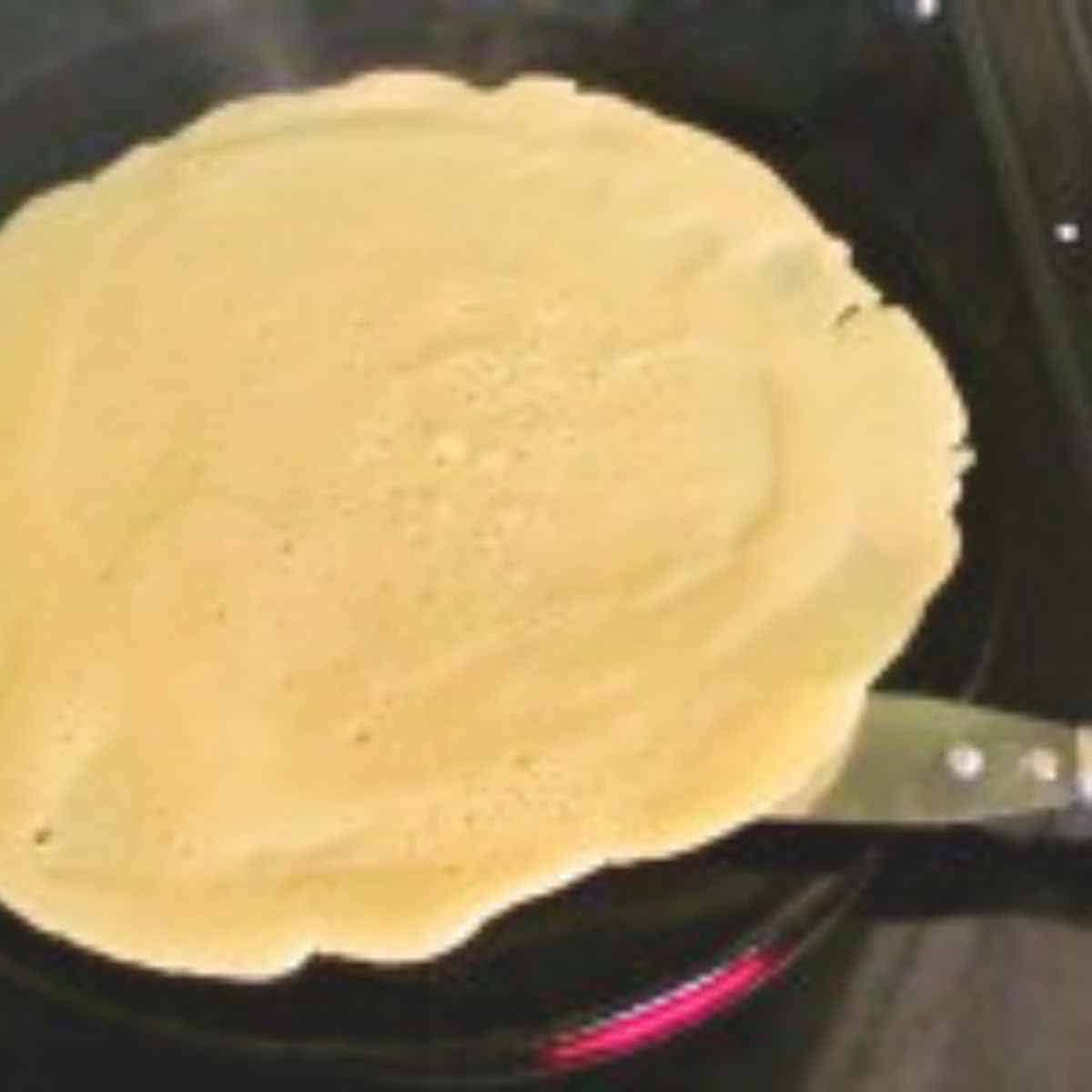 White crepe in a pan ready to flip.