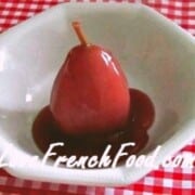 Piece of fruit covered in red sauce in white bowl on red and white cloth.