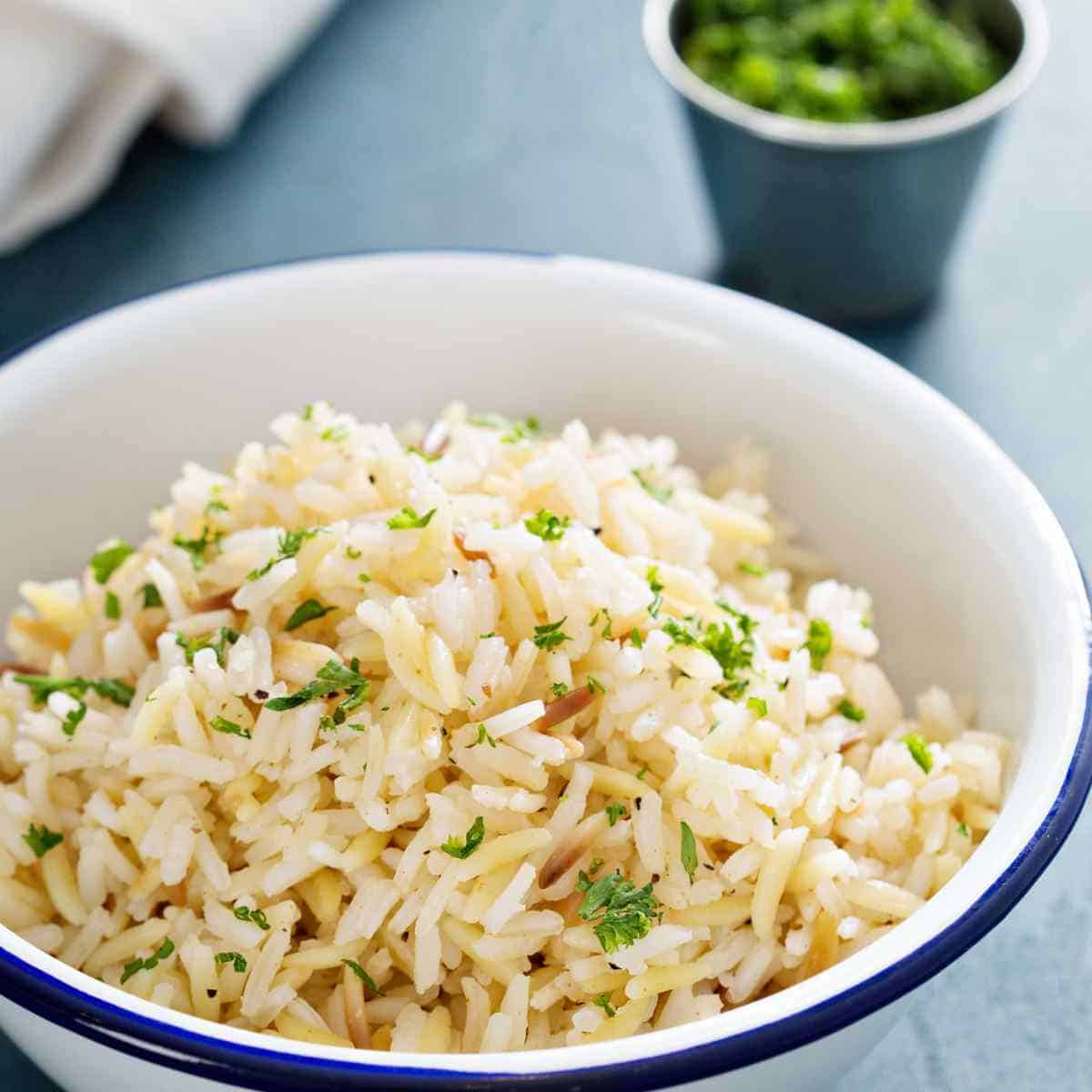 White bowl with rice and green herbs.