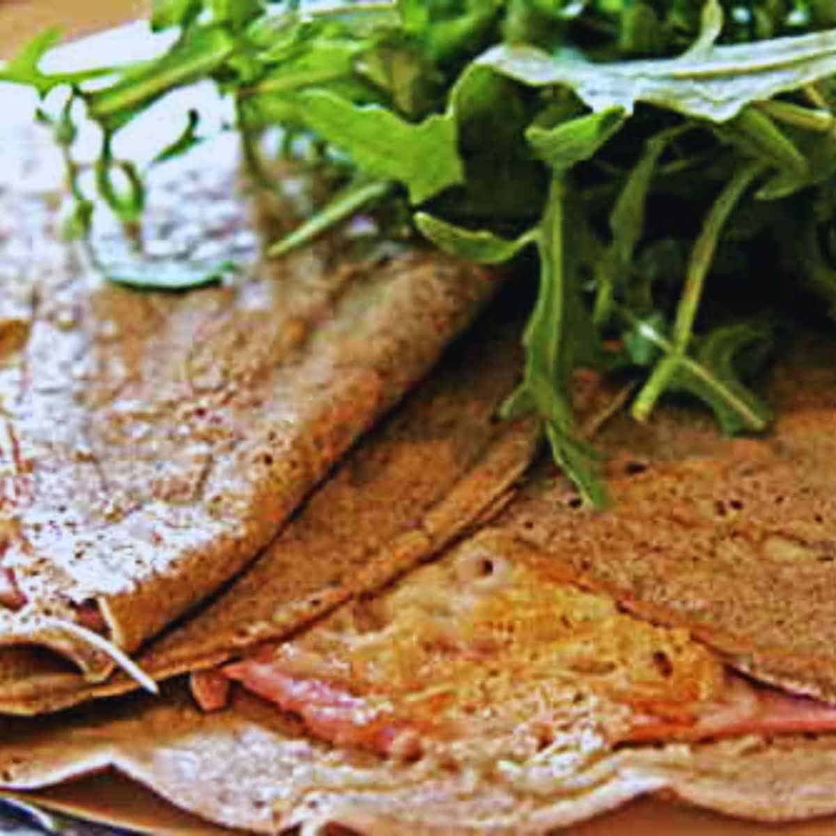 A brown pancake with cheese and greens.