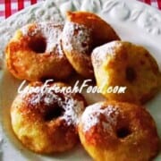 Five golden donuts on a white plate.