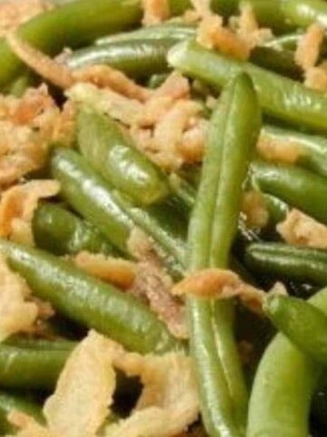 Cooked green beans with golden brown onions mixed together.