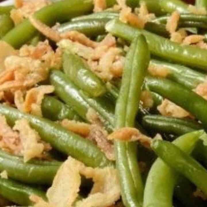 Cooked green beans with golden brown onions mixed together.