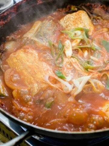 Large pot filled with fish bits and vegetables.