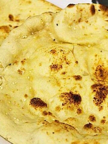 A yellowy, flatbread with puffy spots that are dark brown sprinkled with sesame seed.