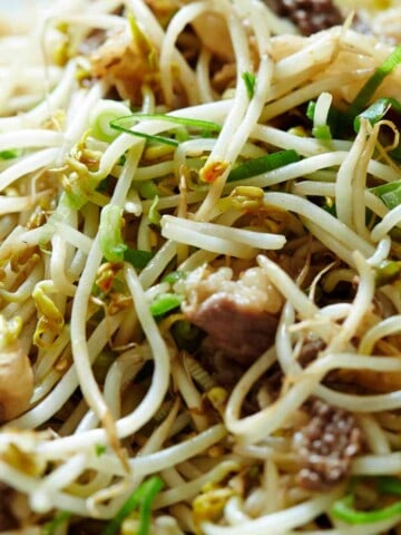 White and green bean sprouts mixed with brown beef slices.