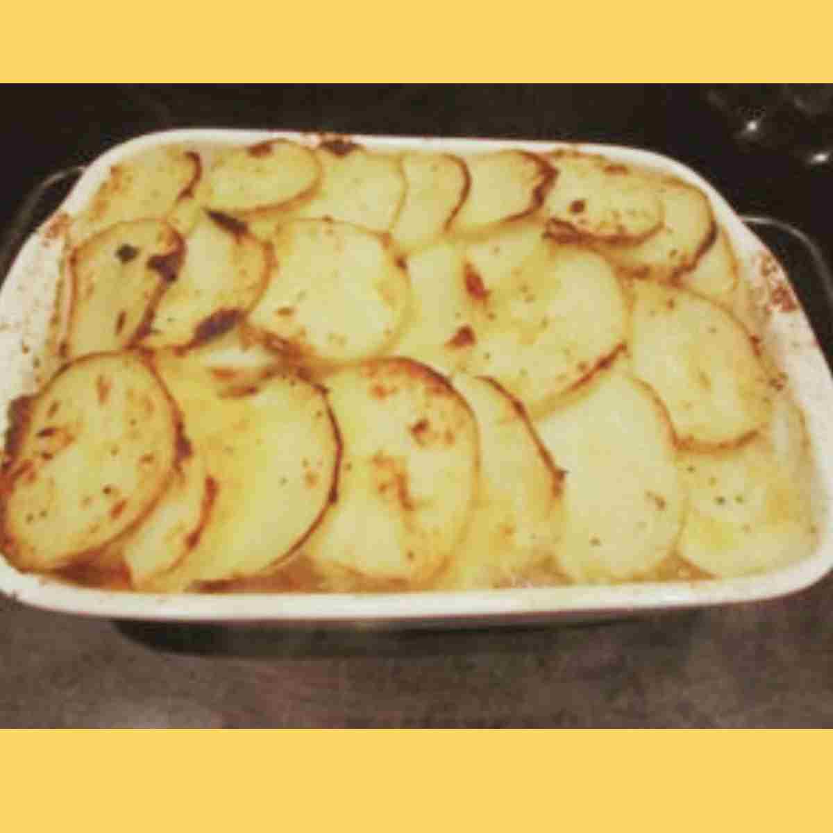 A casserole dish with browned potato slices layered across the top.