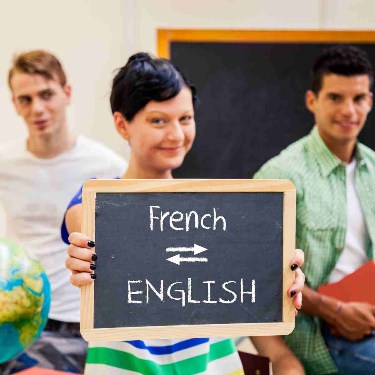 Young woman holding a chalkboard sign with the words French and English written on it with two arrows between them pointing in different directions.