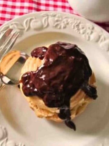 A white plate witha cream colored puff pastry drizzled with dark chocolate.