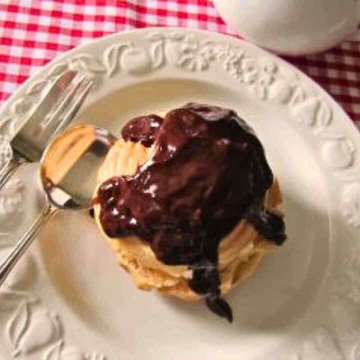 A white plate witha cream colored puff pastry drizzled with dark chocolate.