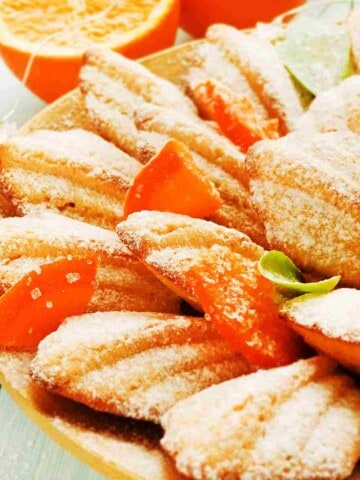 Leaf shaped cake cookies sprinkled with icing sugar and bits of dried orange peel.