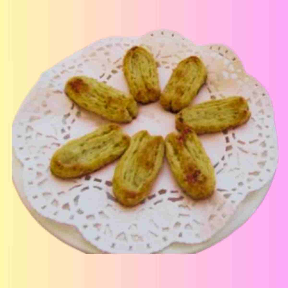 Seven beige puff pastry cookies on a plate laden with a doily.