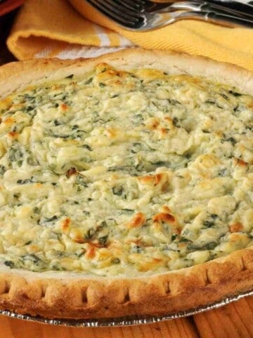 A large egg pie with green spinach and white cheese mixed with the eggs and cooked to light golden color.