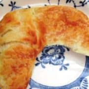 Golden croissant, crescent shaped on a white plate with blue pattern.