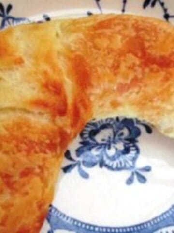 Golden croissant, crescent shaped on a white plate with blue pattern.