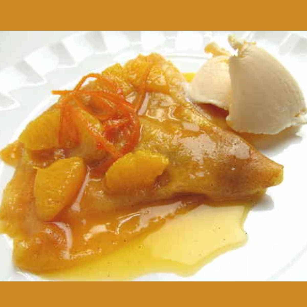 A thin pancake called a crepe with orange citrus sauce and a clump of butter.