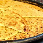 Large black pan filled with golden yellow chickpea flatbread called socca.