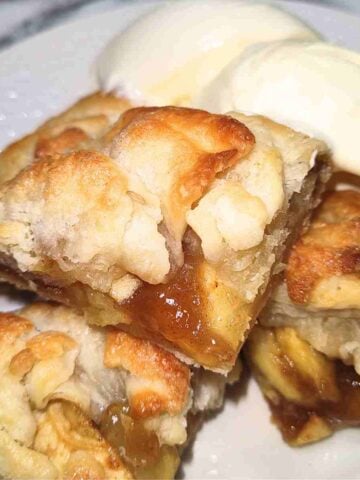 One beige and golden brown galette cut in fours on a white plate with white ice cream on the side.