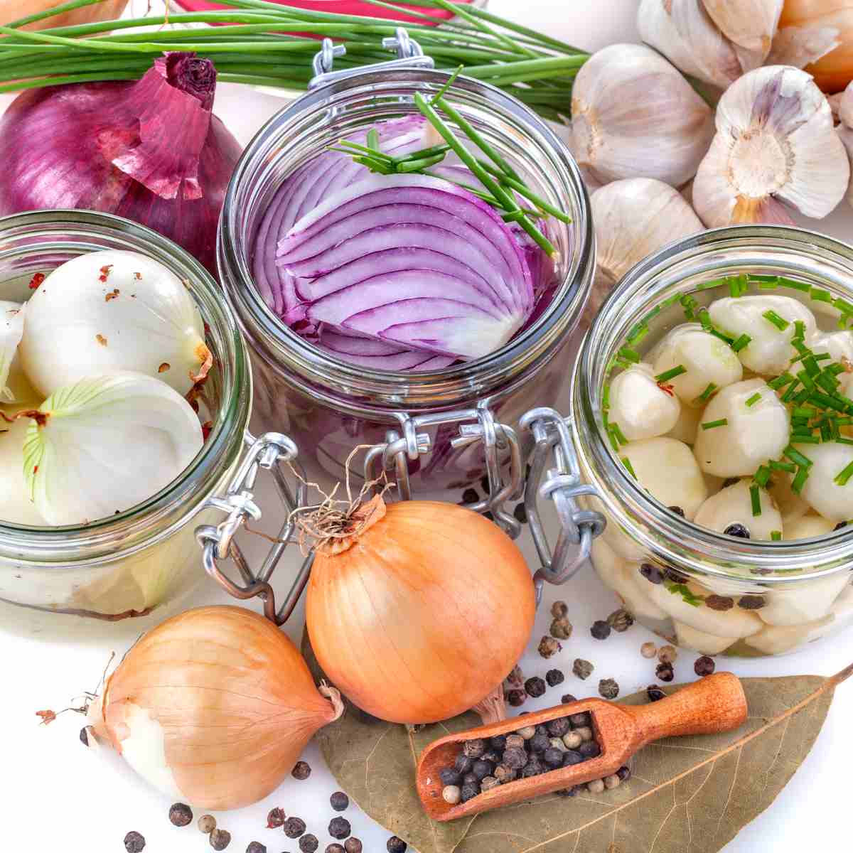 Green chives, white garlic, red, yellow, and white onions. brown bay leaves and black peppercorns.