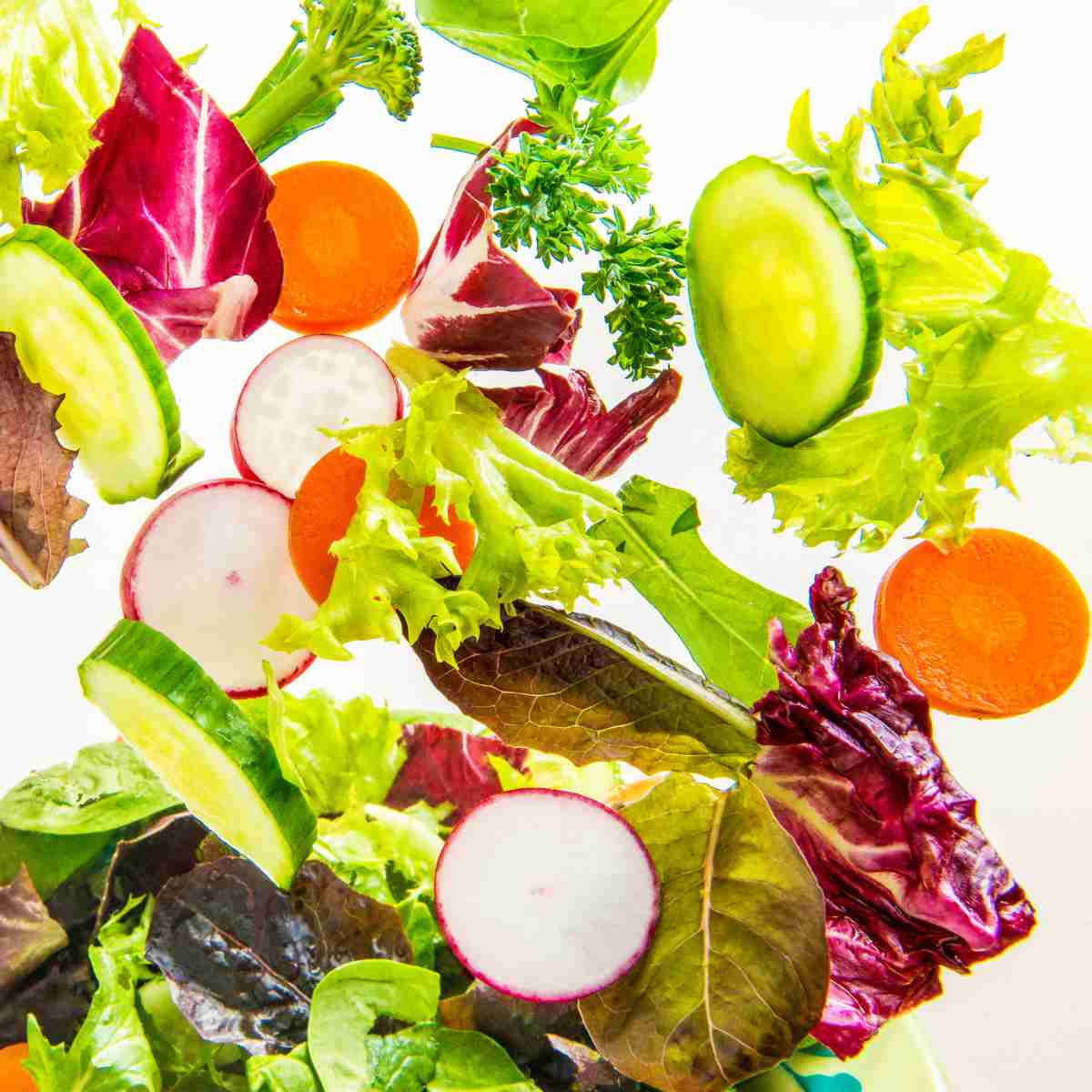 Vegetables of all colors being tossed in the air.