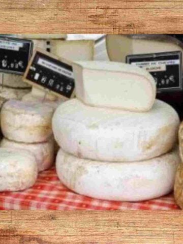 Several different wheels of various types of cheese from France some are white, yellow and light brown.
