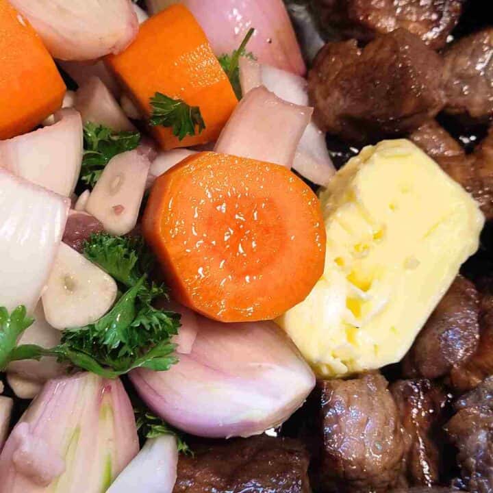 Chopped orange carrots, white onions, green parsley leaves browned meat and a knob of yellow butter.