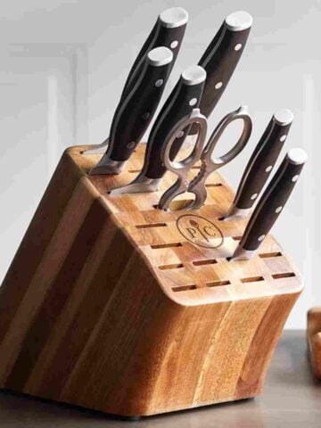 Brown knife block with six black-handled knives and one pair of silver kitchen sheers from Pampered Chef.