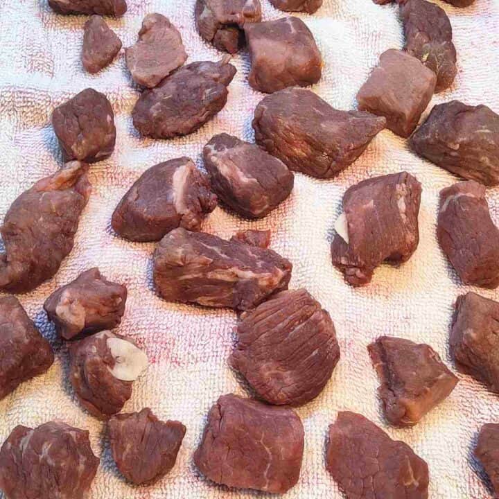 Brown chunks of beef that have been dried on a towel.