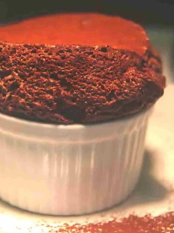 A light fluffy rich dark brown chocolate dessert with bubbles in a white baking dish.