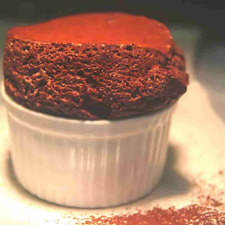 A light fluffy rich dark brown chocolate dessert with bubbles in a white baking dish.
