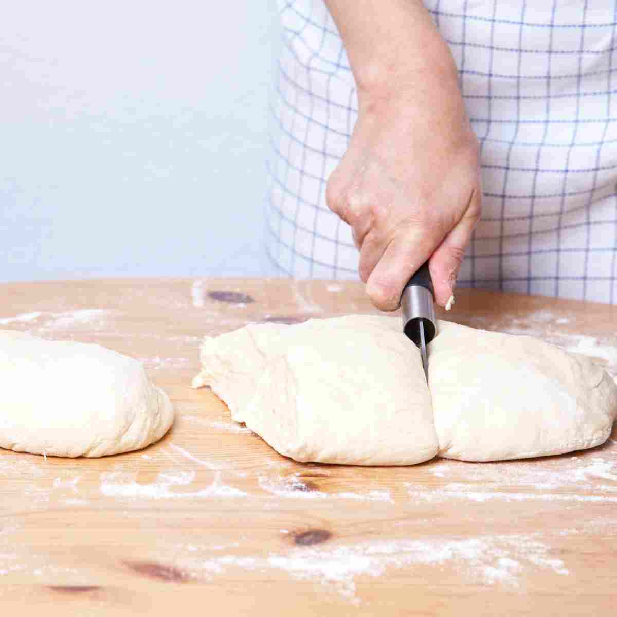 Cutting dough into 3 to prepare for shaping baguette loaves.