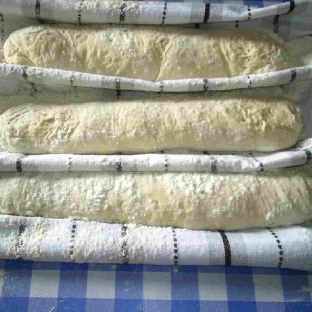 Baguettes are shaped and rising before slicing the tops.