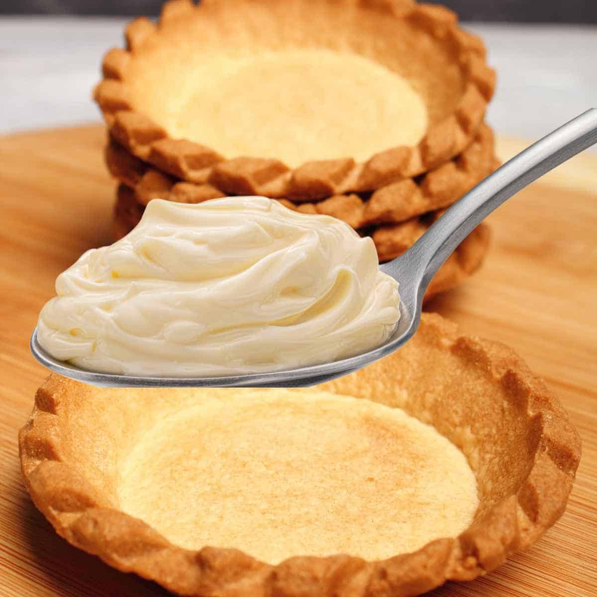 Filling the baked and cooled tart shells with spoonfuls of orange cream cheese.