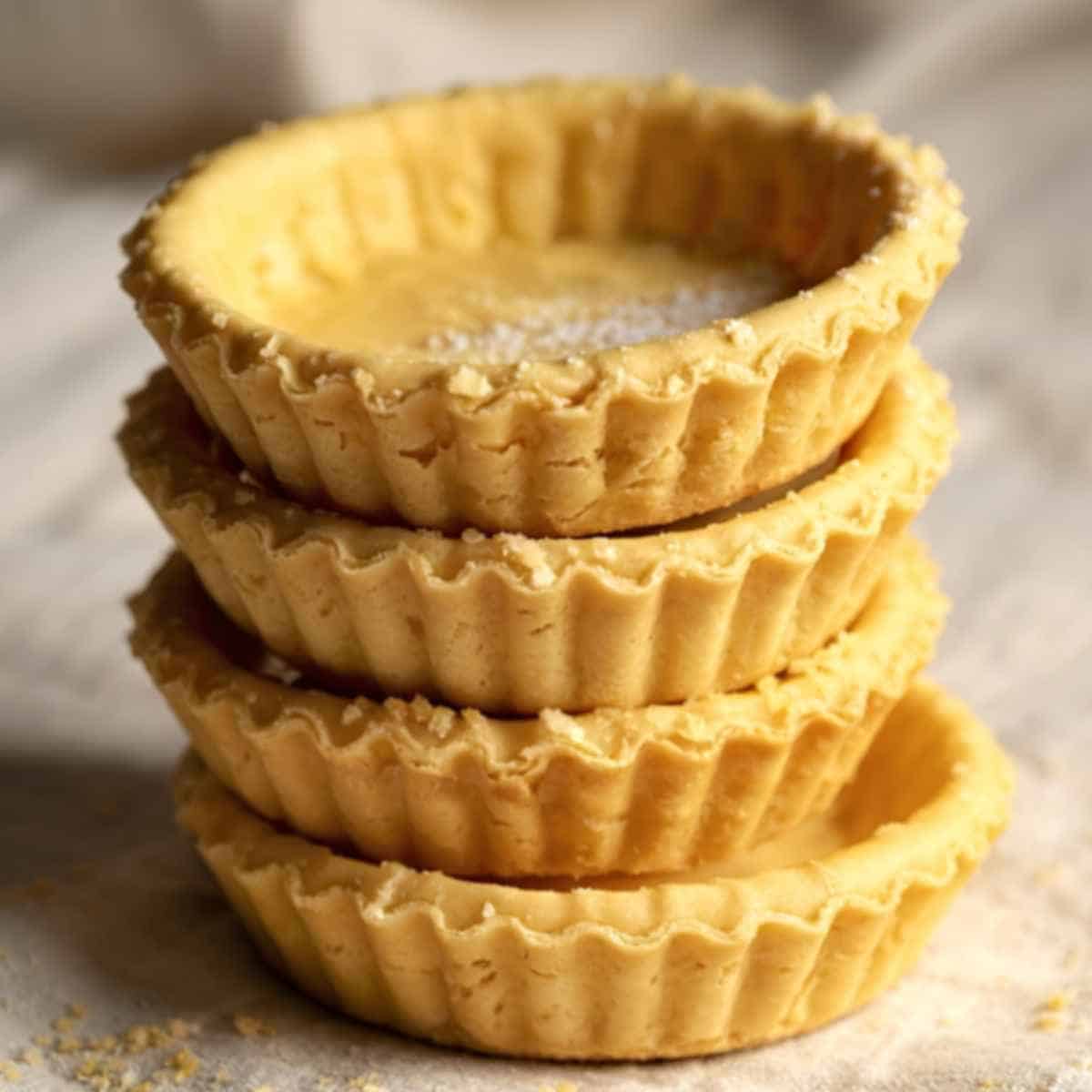 Baked tart shells ready to be filled with orange cream cheese filling and strawberries.